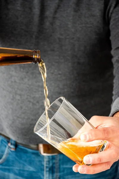 Man serving a craft beer in a wide glass Decanting the beer in a glass. Waiter serving a glass of homemade beer at home. Selected focus. Bottom with bokeh. Close up view.