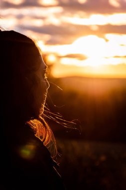 Arkadaki beyaz, beyaz, beyaz kadın. Gün batımında ufka bakıyorum. Dikey görünüm.