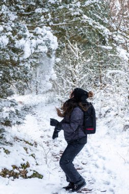 Genç kız karları ağaçlardan kaldırıyor. Karla oynayan yetişkin bir kadın.