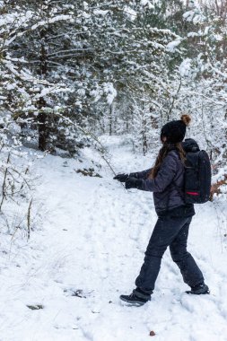 Genç kız ormandaki ağaçların dallarında karla oynuyor. Kar yağarken oynuyorum.