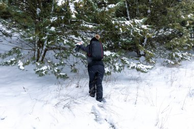 Siyah giyinmiş bir kadın karda kar yağarken donmuş bir ormanda yürüyor. Yatay görüntü. Ormanda karla kaplı çıkmaz yol.