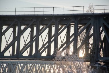 Günbatımında kar ve buzla kaplı ağaçlarla Zamora şehrinin eski tren köprüsü ve demir köprüsü. Yatay görünüm.