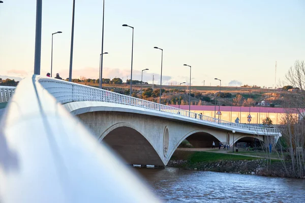 Gün batımında insanların yürüdüğü bir köprünün odak açısının dışında, Bokeh. Beyaz, metalik, odak korkuluğu dışında. Zamora 'daki şairlerin köprüsü.