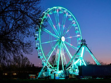 Akşam alacakaranlıkta lunaparkta dönme dolap. Gece partisinin yatay görüntüsü