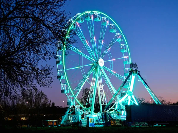 Akşam alacakaranlıkta lunaparkta dönme dolap. Gece partisinin yatay görüntüsü