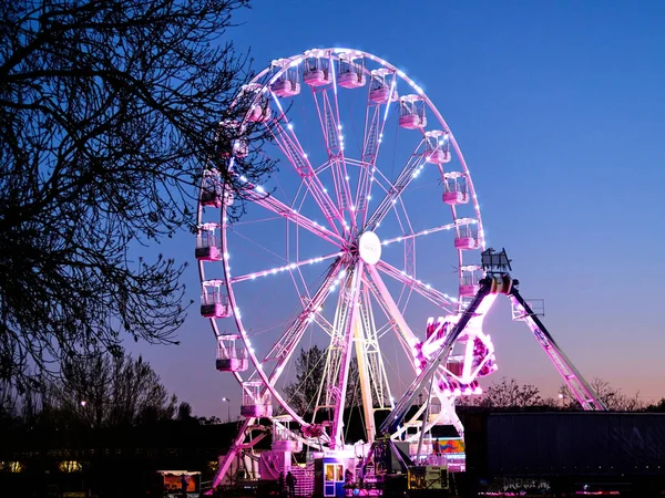 Akşam alacakaranlıkta lunaparkta dönme dolap. Gece partisinin yatay görüntüsü