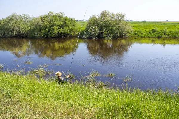 Pescatore in una giornata di pesca estiva sul fiume su un galleggiante — Foto Stock