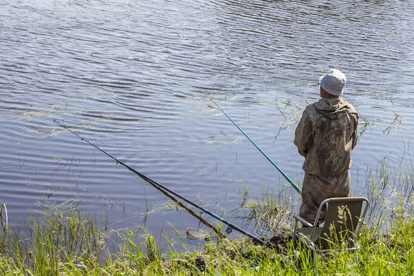 Pescatore in una giornata di pesca estiva sul fiume su un galleggiante — Foto Stock