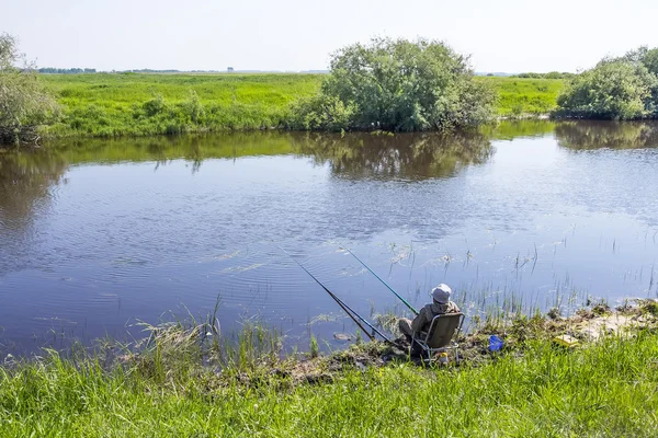 Pescatore in una giornata di pesca estiva sul fiume su un galleggiante — Foto Stock