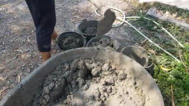 İnşaat işçileri iş için kovalara çimento döküyorlar..