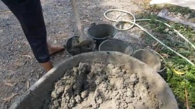 İnşaat işçileri iş için kovalara çimento döküyorlar..