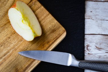 Ağaç kesme tahtasına yanında bir bıçakla yerleştirilmiş bir elma.