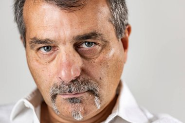 Yüzünde ciddi bir ifade olan olgun bir adamın portresi.