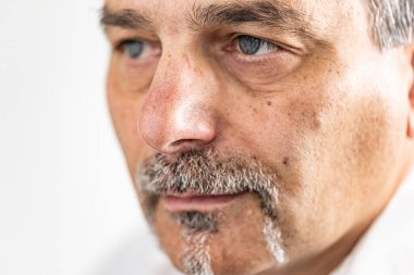 Olgun sakallı iş adamı kamerayı kaçırıyor.