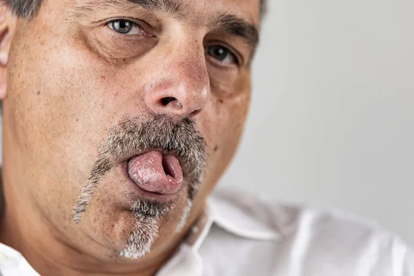 Dilini katlayan sakallı bir adam.