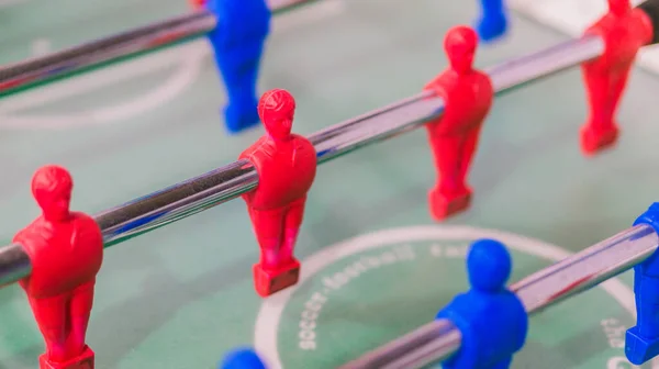 Çelik çubuk üzerinde kırmızı ve mavi masa futbolcusu izole, yeşil arka saha