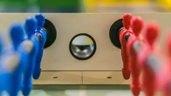 Çelik çubuk üzerinde kırmızı ve mavi masa futbolcusu izole, yeşil arka saha