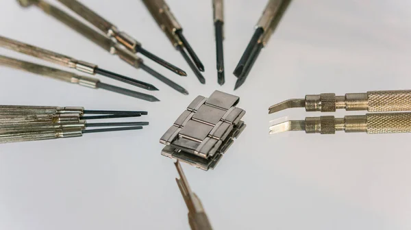 Bahar barı aletini kullanan bir saatçi. Yay çubuklarını kaldırmak için kullanılan yay çubuğu aracı saat kayışını değiştirmek için.