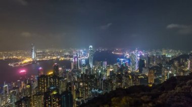 Hong Kong şehir manzarası timelapse Victoria Limanı ve dağ üstten Bakınlan su üzerinde ışıklar tarafından aydınlatılmış gökdelenler ile gece.