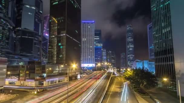 Hong Kong Business District timelapse en la noche. Edificio corporativo en la parte trasera y tráfico ocupado a través de la carretera principal en hora punta . — Vídeo de stock