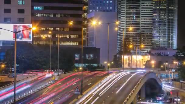Hong kong Geschäftsviertel Zeitraffer in der Nacht. Firmengebäude im Hintergrund und reger Verkehr im Berufsverkehr über die Bundesstraße. — Stockvideo