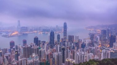 Victoria Peak gece gündüz timelapse Hong Kong ünlü görünümü. Kowloon Körfezi üzerinde renkli bulutlar ile gün doğumundan önce alınan.