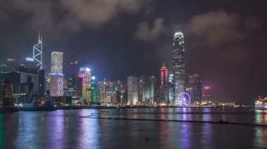 Bulutlu gökyüzü ve kentsel gökdelenler zaman aşımı hiperlapse ile Victoria Harbor üzerinde gece Hong Kong şehir silueti.