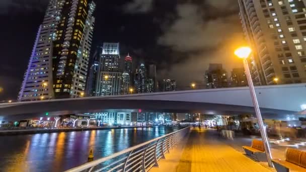 Paseo en el paseo marítimo de Dubai Marina con vista a las torres y el canal en Dubai noche timelapse hiperlapso — Vídeo de stock