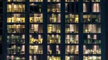Cam ve çelik ışıklandırmadan oluşan çok katlı binanın penceresi ve zaman ayarlı insanlar