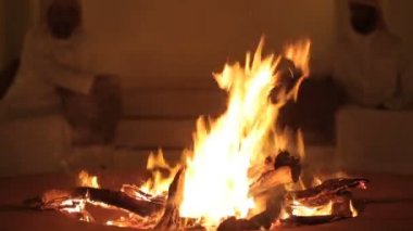 İnsanlar gece parlak bir şenlik ateşi arkasında oturmak