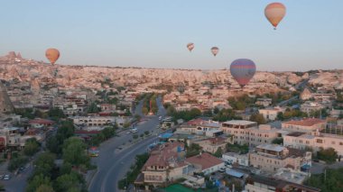 Güneş doğarken, Kapadokya 'nın peri masalı tepeleri üzerinde sabah güneşiyle birlikte diğer uçan balonlarla sıcak hava balonundan hava manzarası. Goreme, Kapadokya, Türkiye