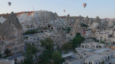 Güneş doğarken, Kapadokya 'nın peri masalı tepelerinde sabah ışığı altında sıcak hava balonundan ve eski evlerden hava manzarası. Goreme, Kapadokya, Türkiye