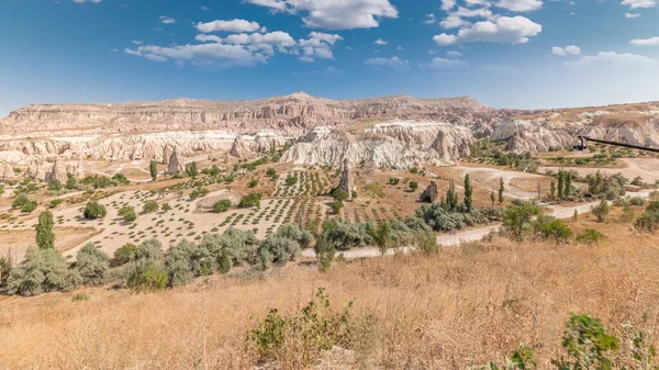 Red Valley and Rose Valley of Goreme of Nevsehir in Cappadocia aerial timelapse, Turkey. Love valley and fairy chimneys panoramic view with clouds on a blue sky