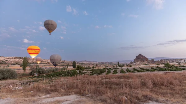 在土耳其的卡帕多西亚 美丽的五彩斑斓的热气球在清澈的夜空中起飞飞翔 在不寻常的岩石景观中掠过 — 图库照片