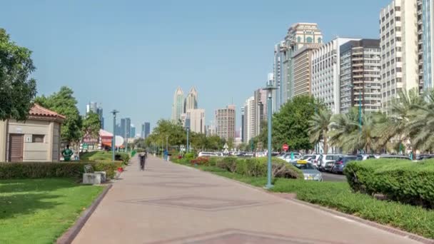 Taman pantai Corniche boulevard di sepanjang garis pantai di Abu Dhabi timelapse dengan pencakar langit di latar belakang. — Stok Video