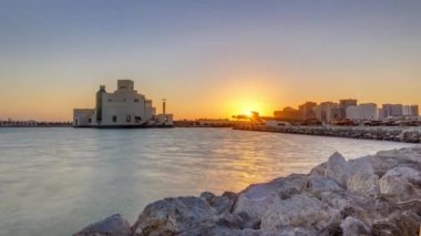 Güneş doğarken geçen balıkçı tekneleriyle Doha Limanı ve arka planda İslami Sanat Müzesi.