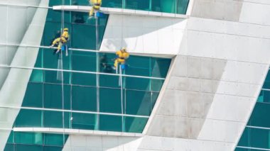 Modern gökdelen binasının camlarını temizleyen işçiler