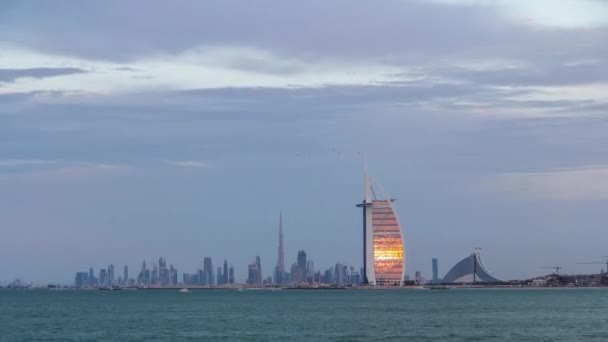 Ντουμπάι ορίζοντα με Burj Al Arab ξενοδοχείο κατά τη διάρκεια του ηλιοβασιλέματος και της ημέρας με τη νύχτα timelapse. — Αρχείο Βίντεο