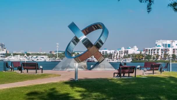 Monumento anillo, banco, césped verde, flores y árboles en Dubai Creek parque timelapse. Dubai, Emiratos Árabes Unidos — Vídeos de Stock