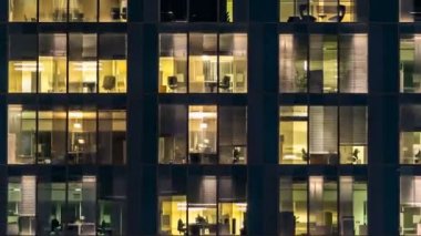 Cam ve çelik ışıklandırmadan oluşan çok katlı binanın penceresi ve zaman ayarlı insanlar