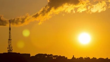 Roma gün batımında güneşin ateşli küre ile tarihi binaların çatıları üzerinde ufuk altında bırakarak zaman aşımı
