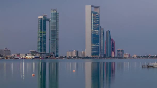 Abu Dhabi skyline città con grattacieli prima dell'alba con riflesso dell'acqua notte per giorno timelapse — Video Stock