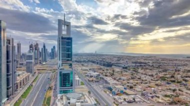 Dubai gökdelenleri, gün batımı akşam vakti. Dubai Metro İstasyonu ve Şeyh Zayed Yolu üzerindeki trafik