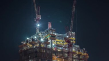 Vinçler, yeni gökdelen zaman çizelgesinin modern soyutlama sahasında geceleri çalışıyorlar.