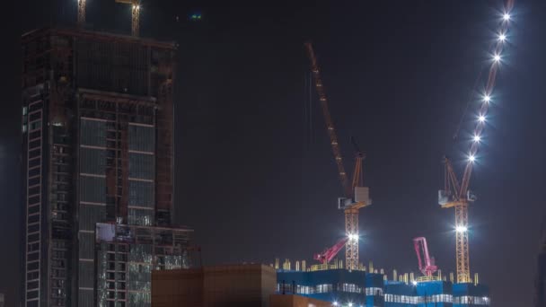 Kranar som arbetar på moderna tvång webbplats verk av nya skyskrapa timelapse på natten — Stockvideo