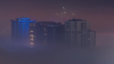Binalar Business Bay 'de gece vakti yoğun sis tabakasıyla kaplıdır..