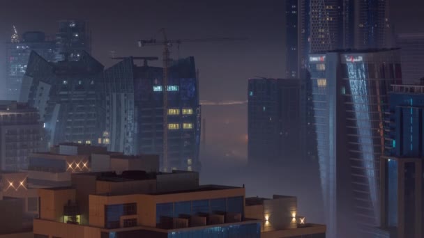Les bâtiments sont recouverts d'une épaisse couche de brouillard dans le timelapse de nuit Business Bay. — Video