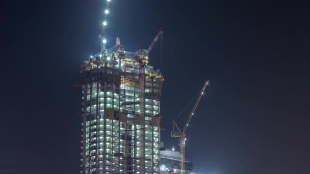 Dźwigi pracujące nad nowoczesnym terenem ograniczającym prace nowego wieżowca w nocy timelapse — Wideo stockowe