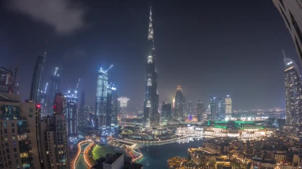 Arranha-céus subindo acima do centro de Dubai durante toda a noite timelapse cercado por edifícios modernos vista aérea superior — Vídeo de Stock