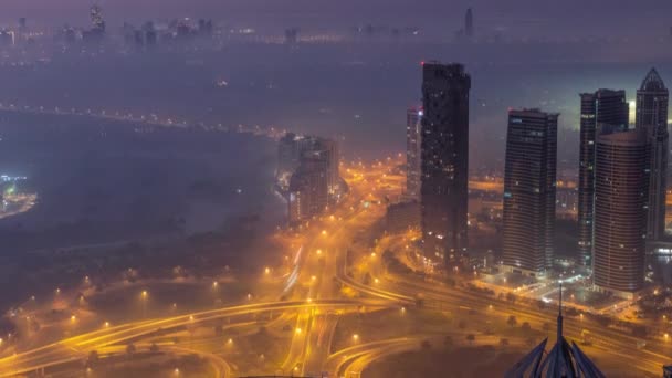 Gran cruce de caminos entre el distrito JLT y el puerto deportivo de Dubái intersecado por Sheikh Zayed Road noche aérea al día timelapse. — Vídeos de Stock